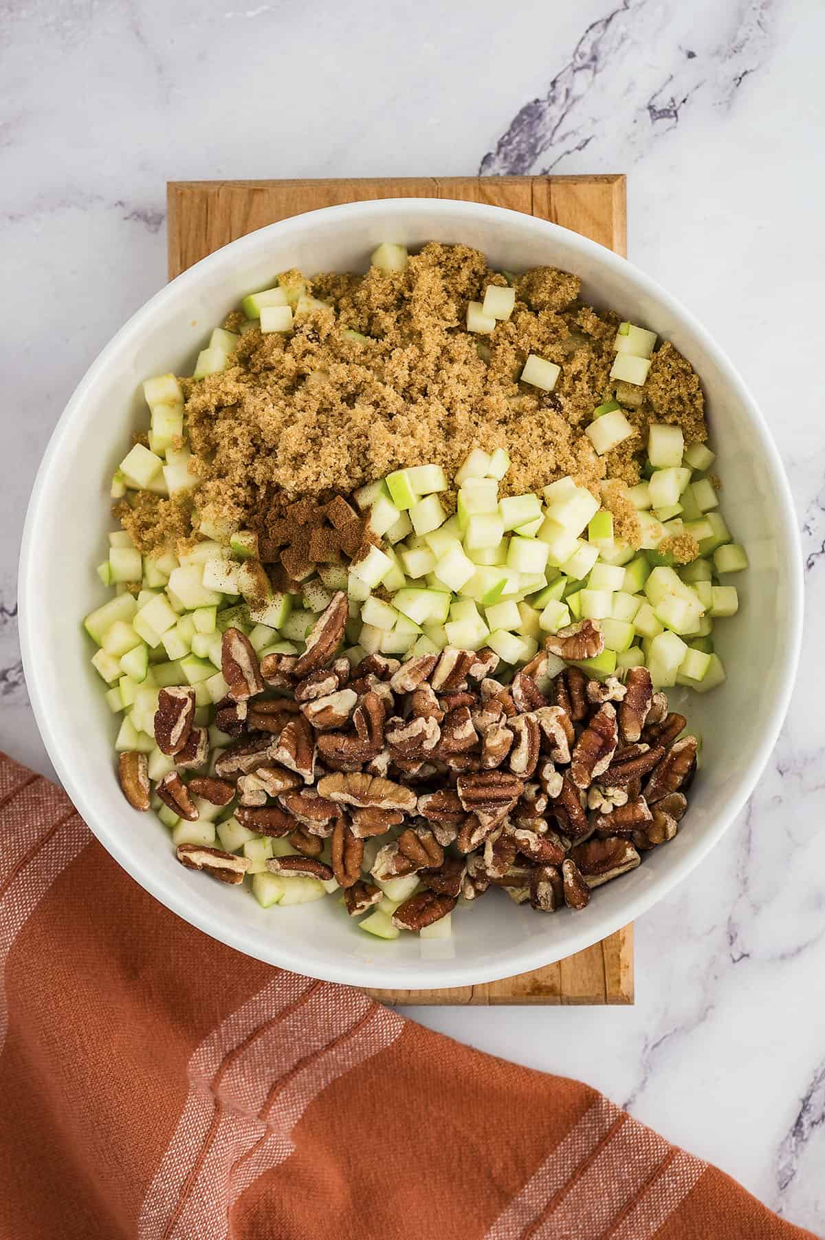 Apples and pecans in bowl with brown sugar and cinnamon.