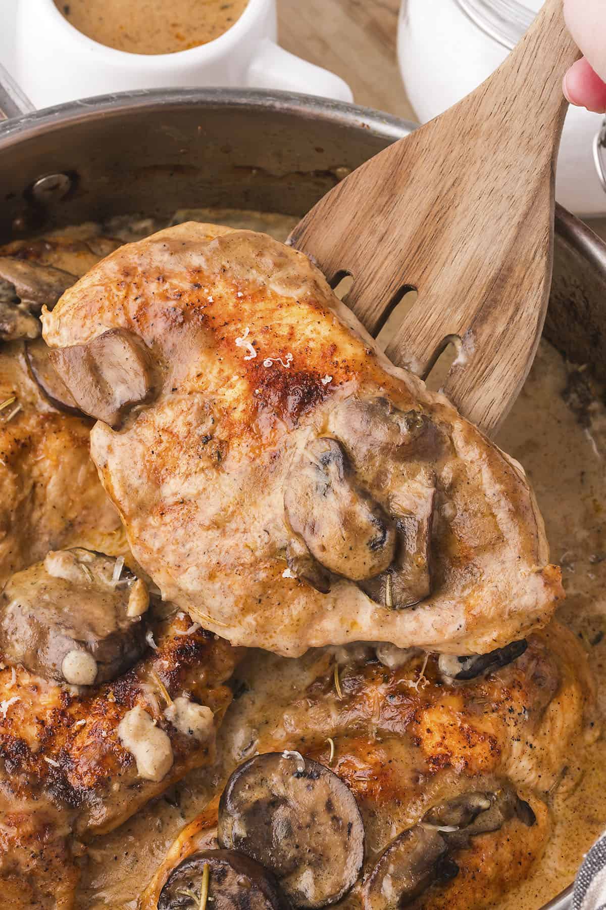 Chicken with cream of mushroom soup on wooden spoon.