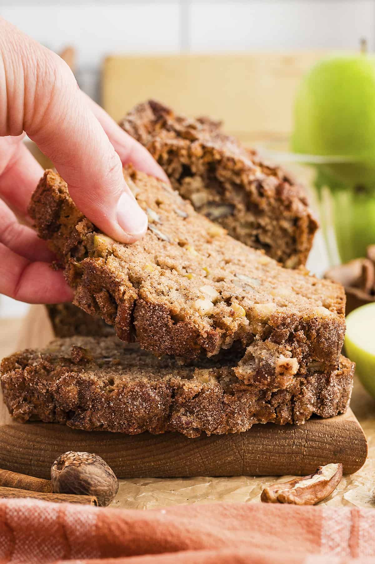 Hand grabbing a slice of apple bread.