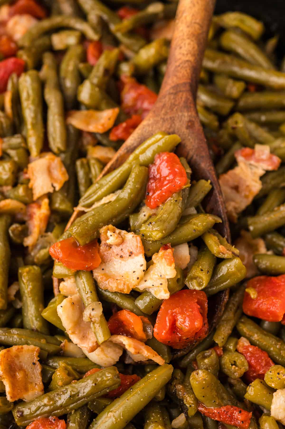 Canned green beans recipe in skillet on wooden spoon.