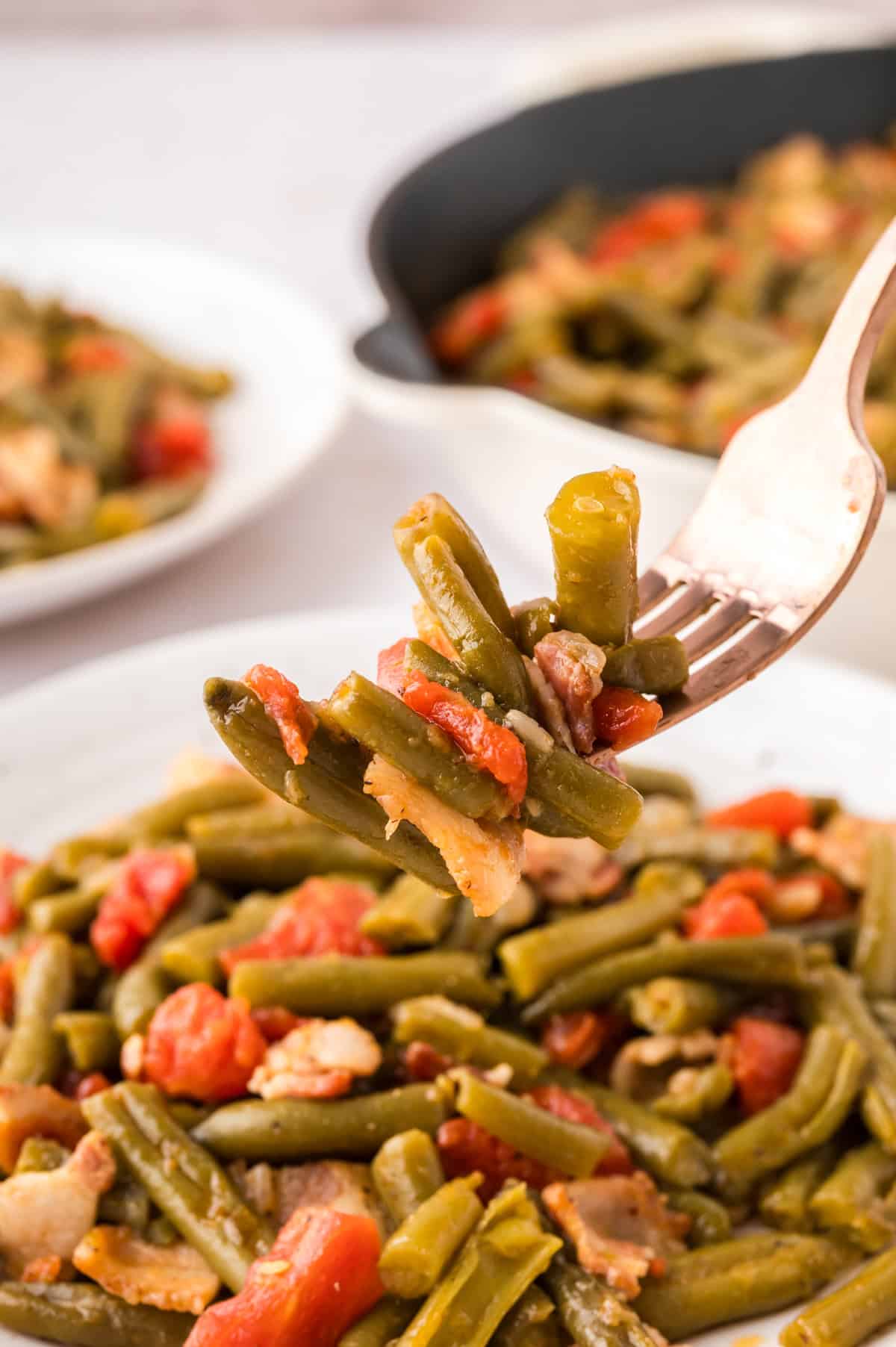 Green beans with bacon and onions on a fork.