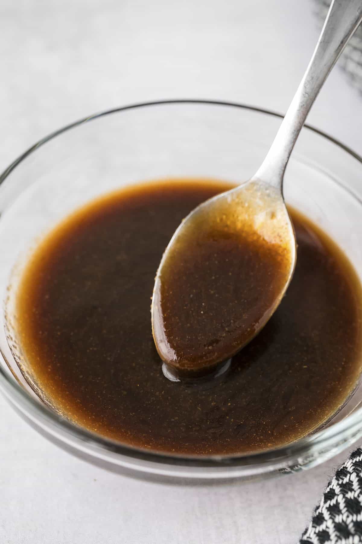 Egg roll sauce dripping off spoon into bowl.