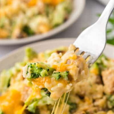 Forkful of chicken broccoli casserole topped with cheese.