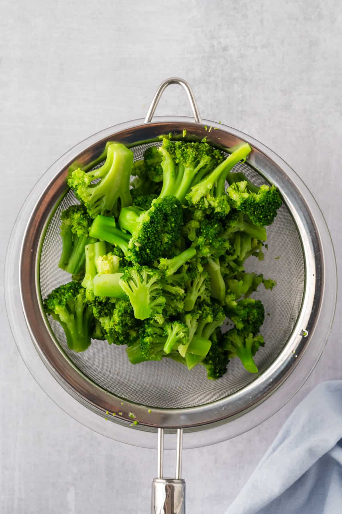 Cooked broccoli in colander.