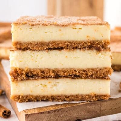 Stack of cheesecake bars on cutting board.