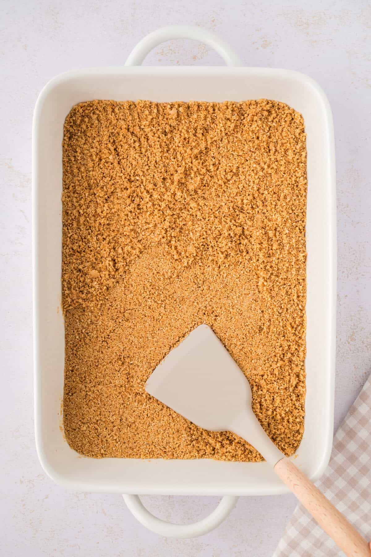 Graham cracker crust being pressed into pan.