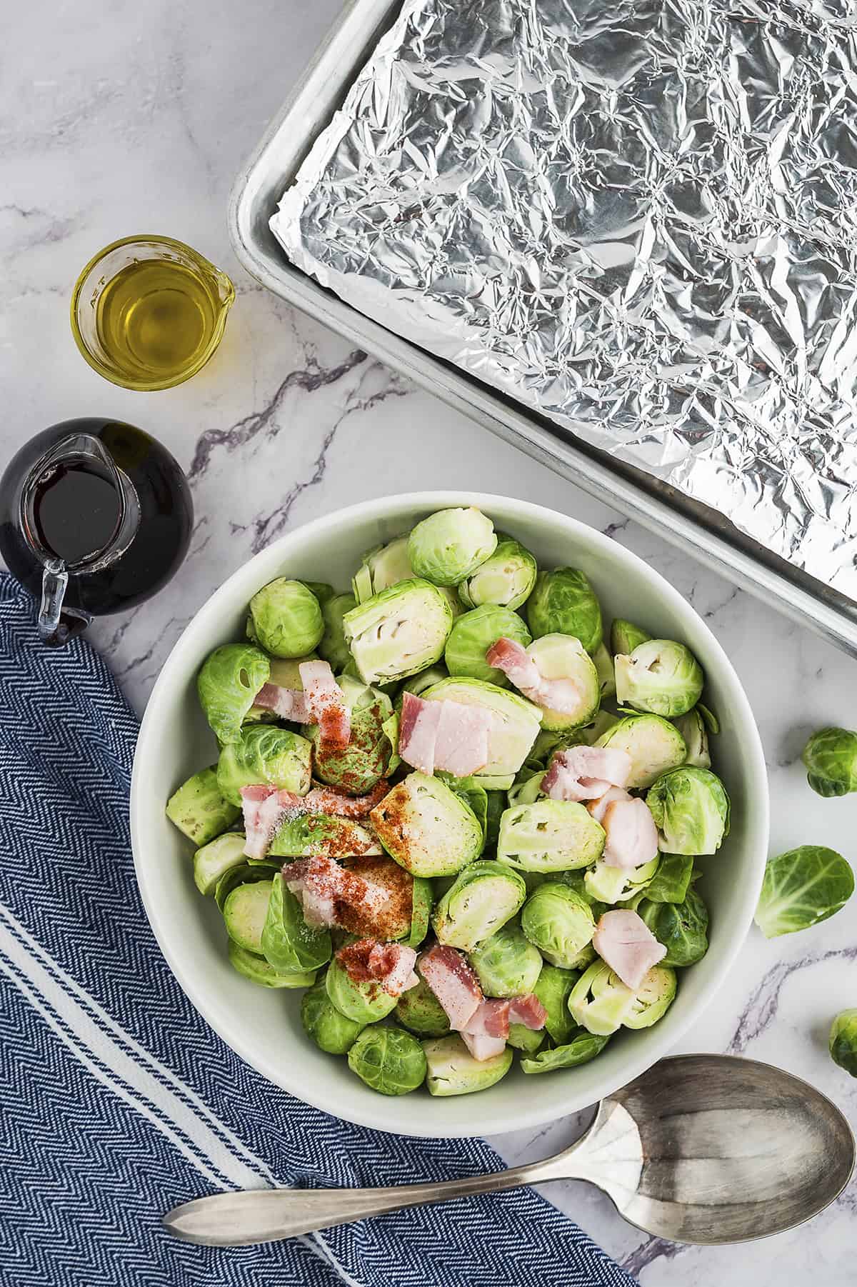 Halved brussels sprouts in bowl with bacon and spices.