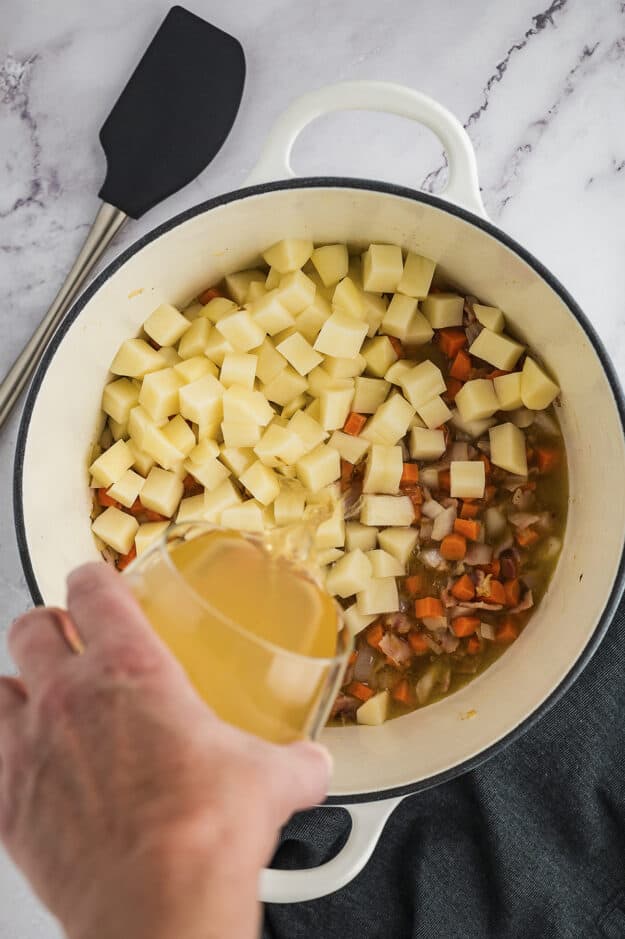 Potatoes and carrots in the pot with chicken broth.