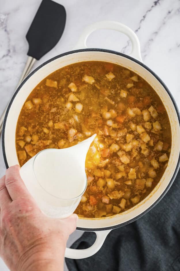 Milk and flour being added to soup.