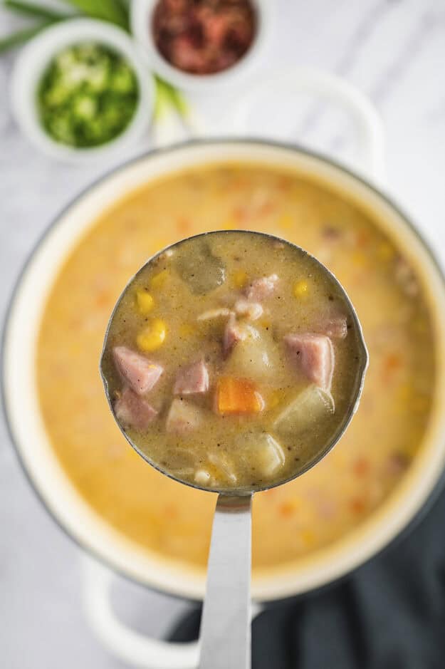 Ham and corn chowder on a ladle.