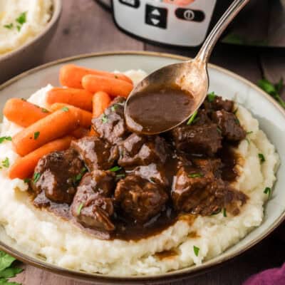 Gravy being drizzled off spoon over beef tips.