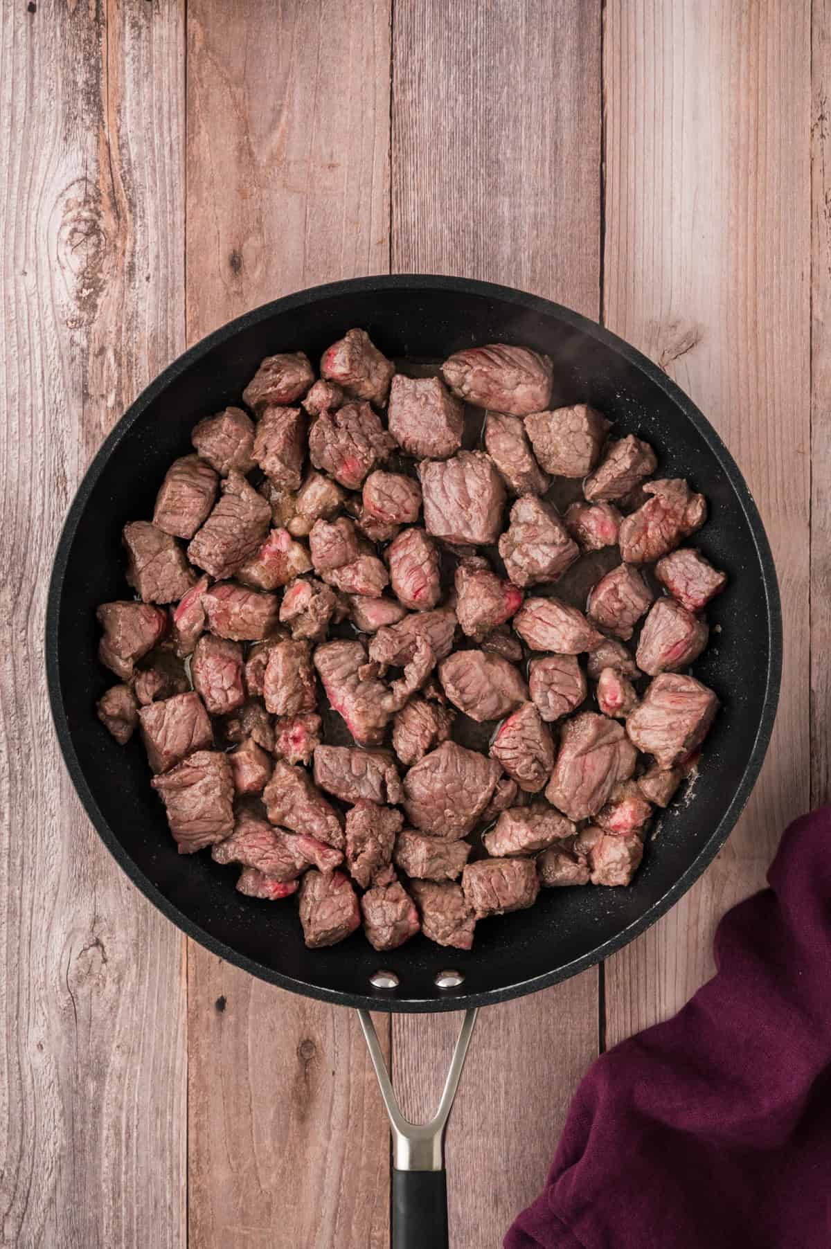 Beef tips being browned in a skillet.