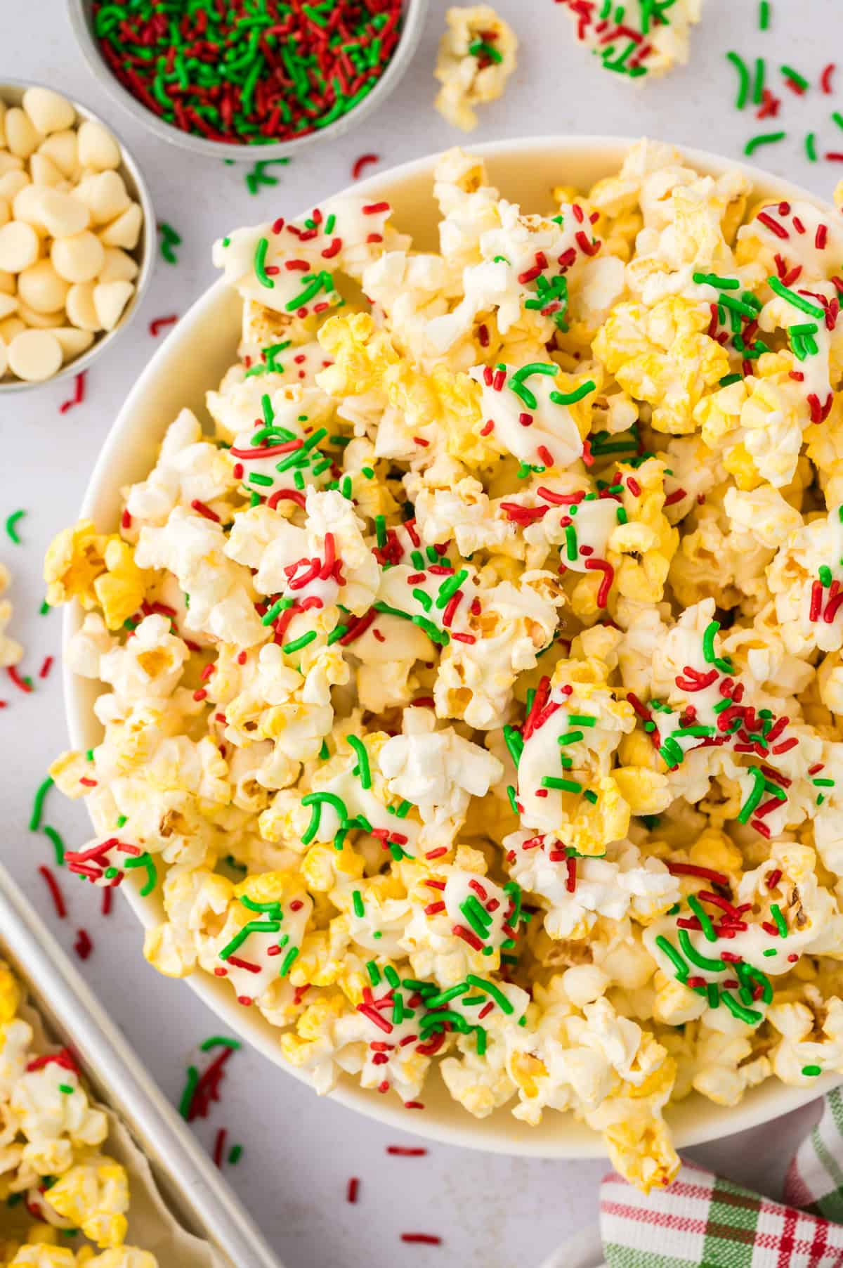 Close up of white chocolate popcorn topped with Christmas sprinkles in white bowl.