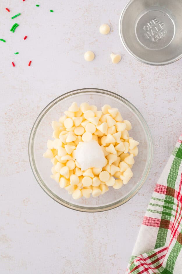 White chocolate chips and coconut oil in small glass bowl.