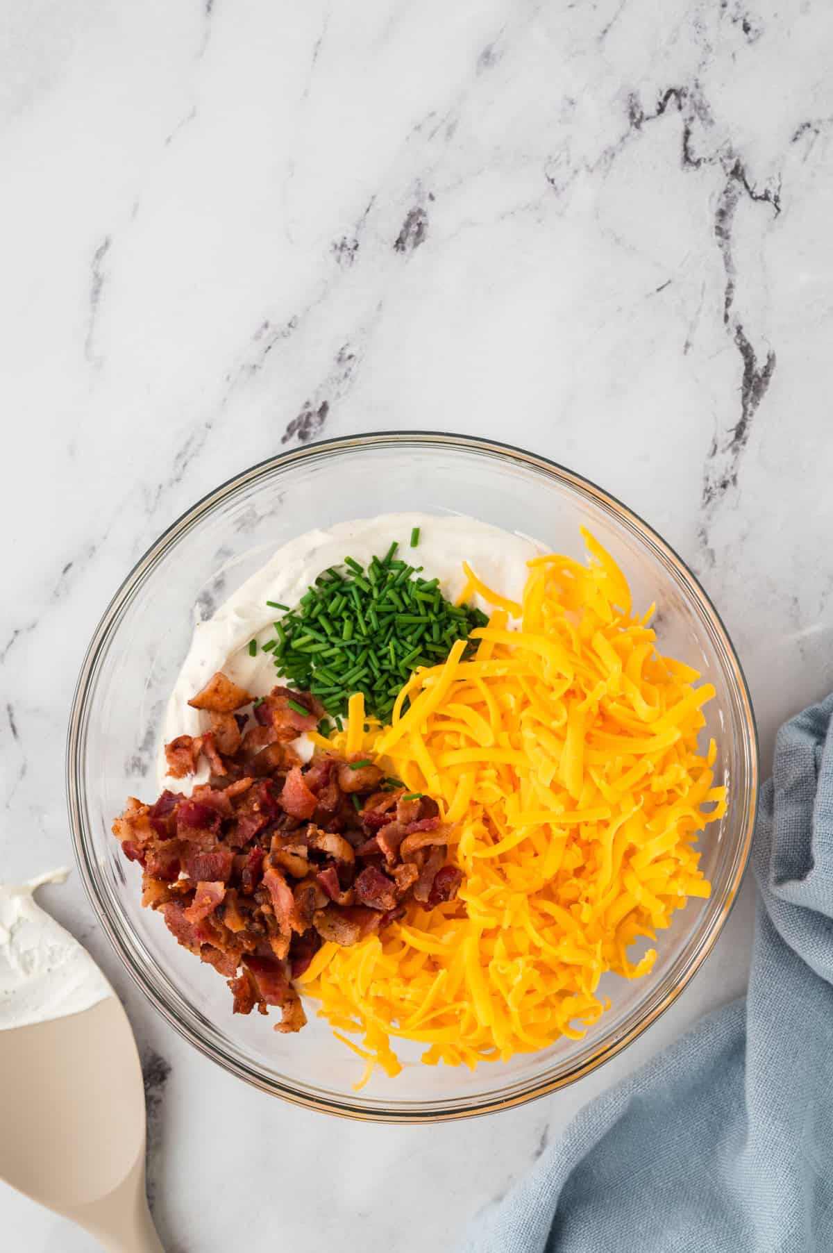 Cheddar, bacon, and chives in bowl of ranch dip.