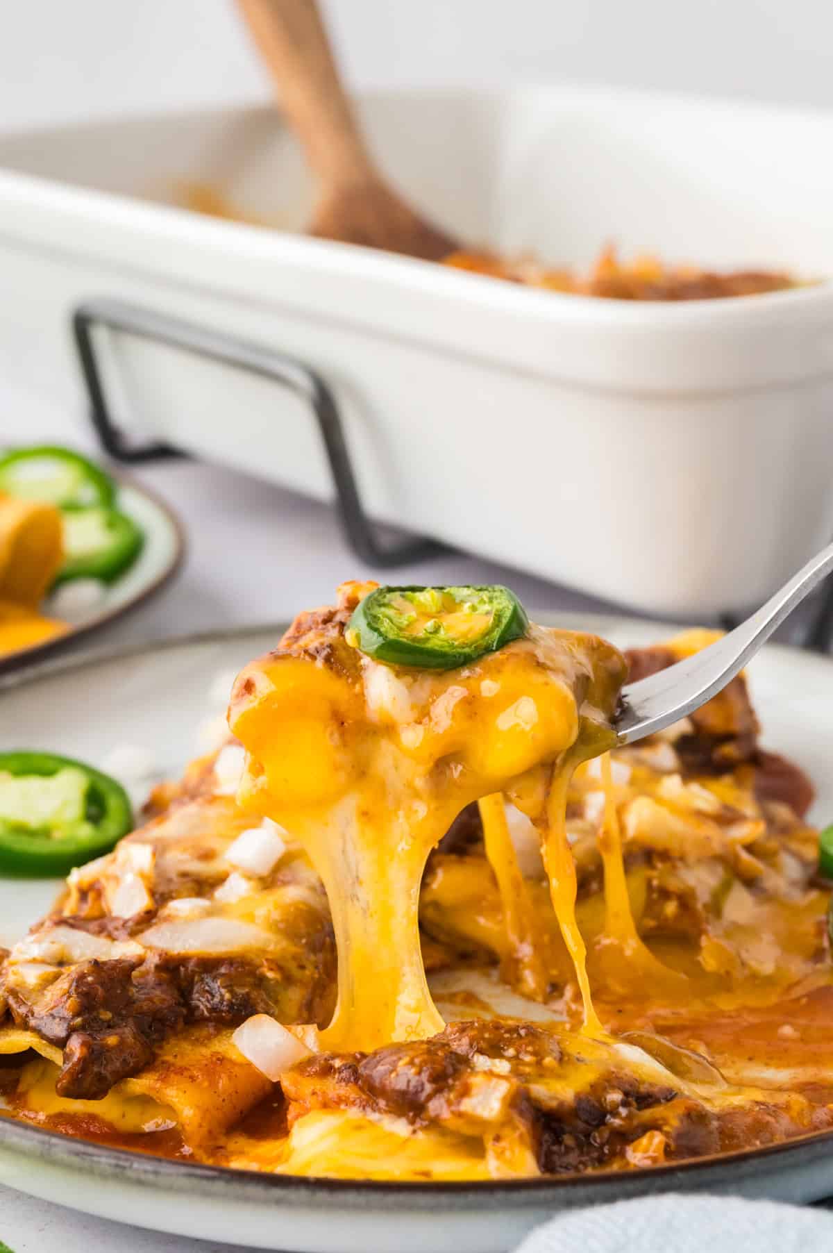 Fork full of chili cheese enchiladas.