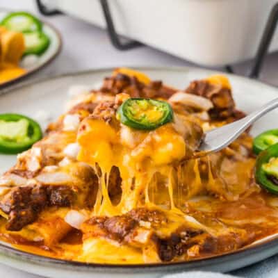 Forkful of cheese enchiladas topped with chili.