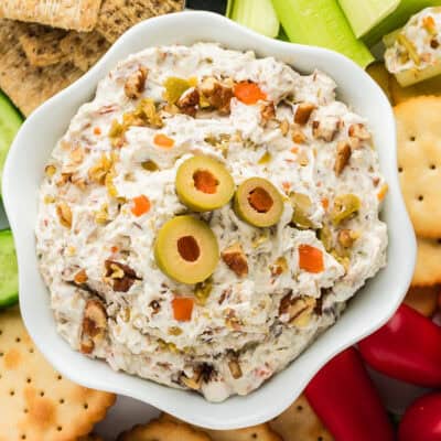 Olive spread in white bowl on veggie and cracker tray.