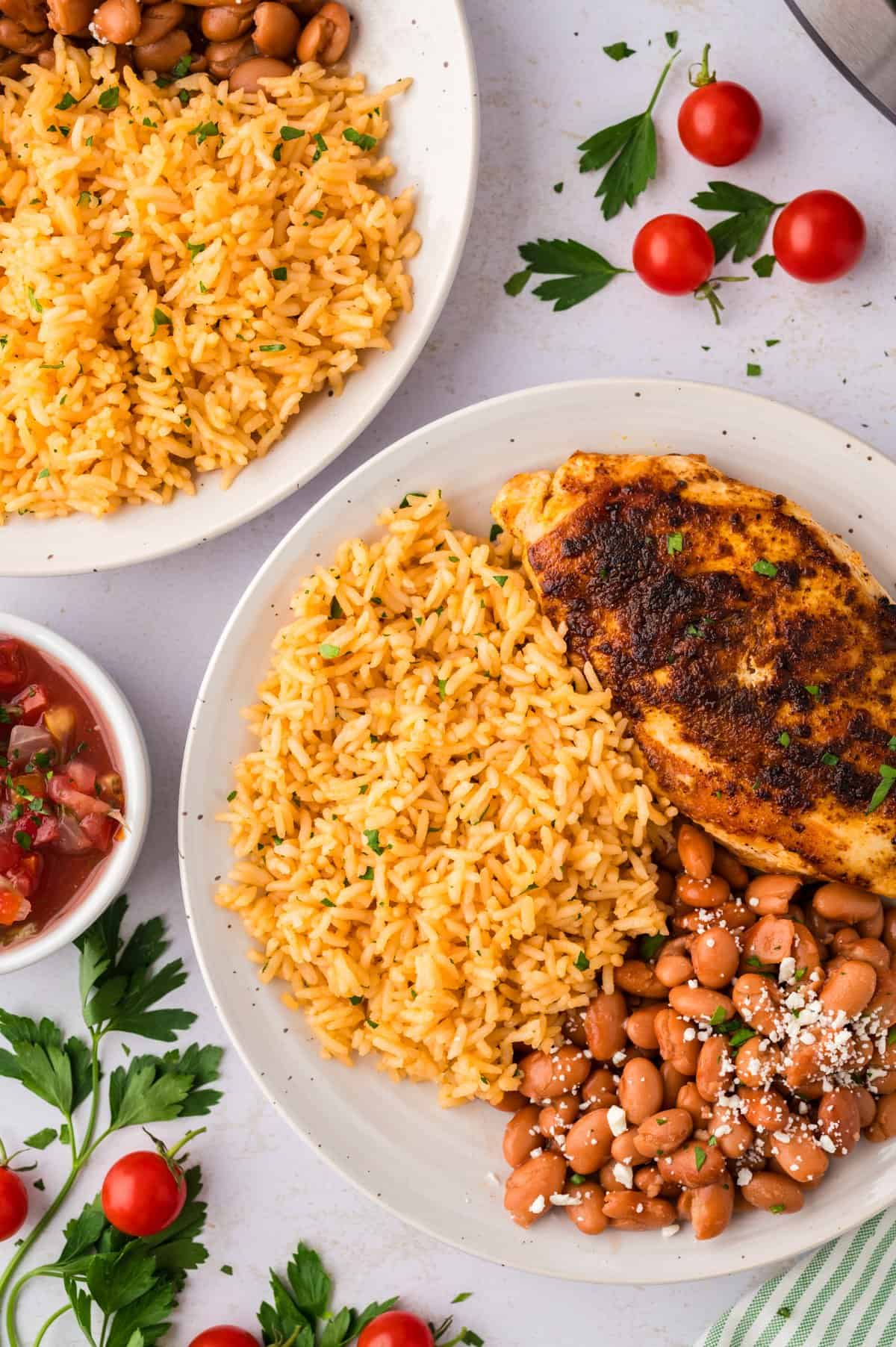 Plate full of Mexican rice, pinto beans, and grilled chicken.