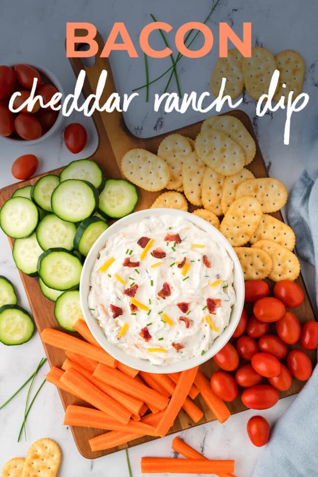 Bacon cheddar ranch dip on board with vefetables and crackers.