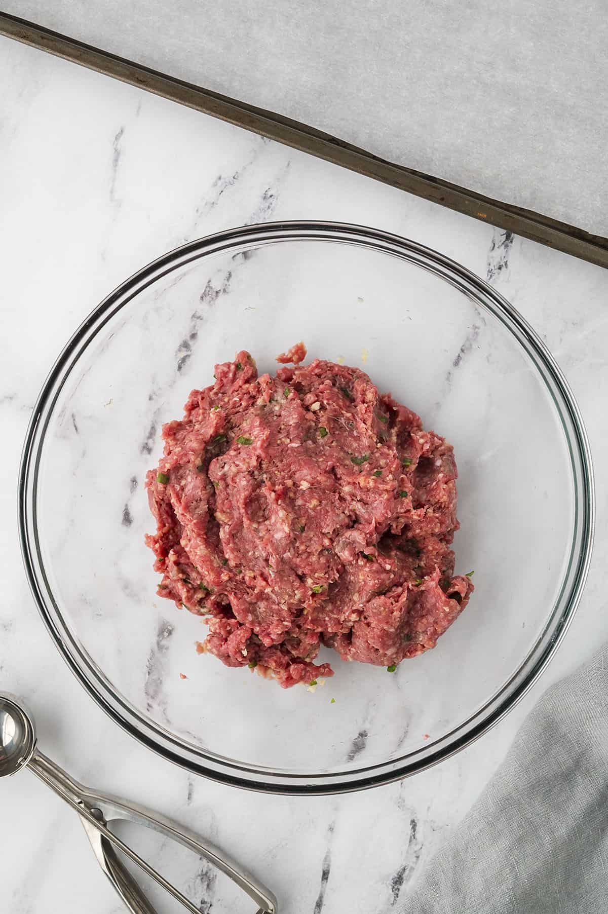 Ingredients for meatballs mixed together in glass bowl.