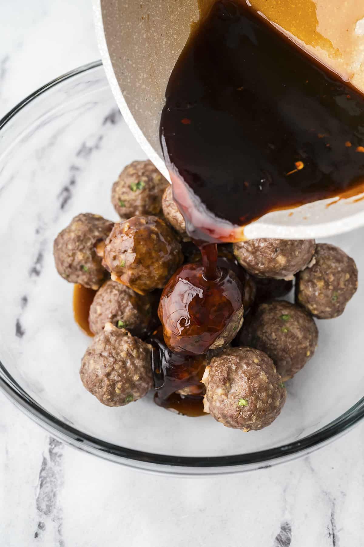 Sauce being poured over meatballs.