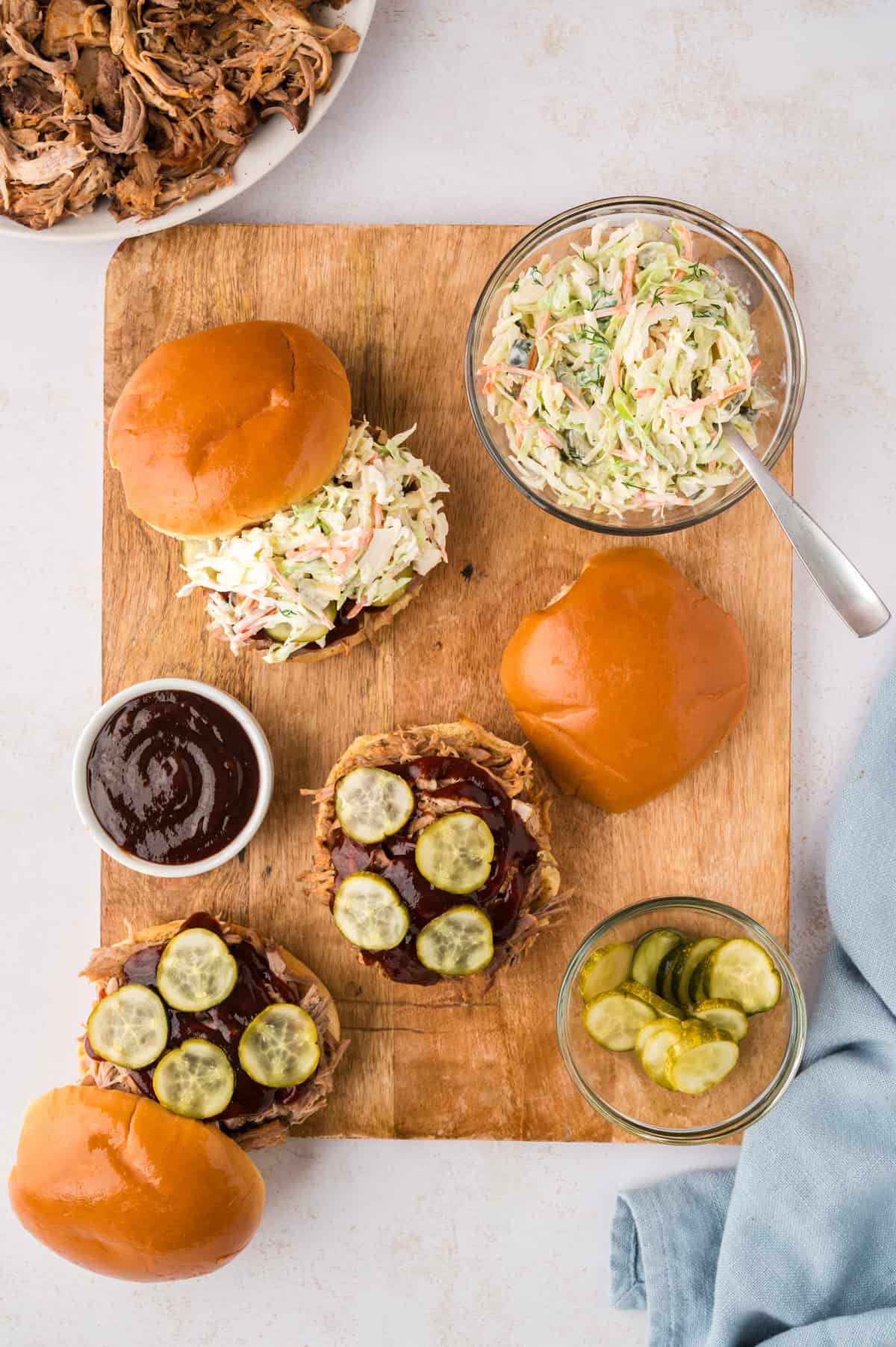 Pulled pork sandwiches topped with barbecue, pickles, and slaw.