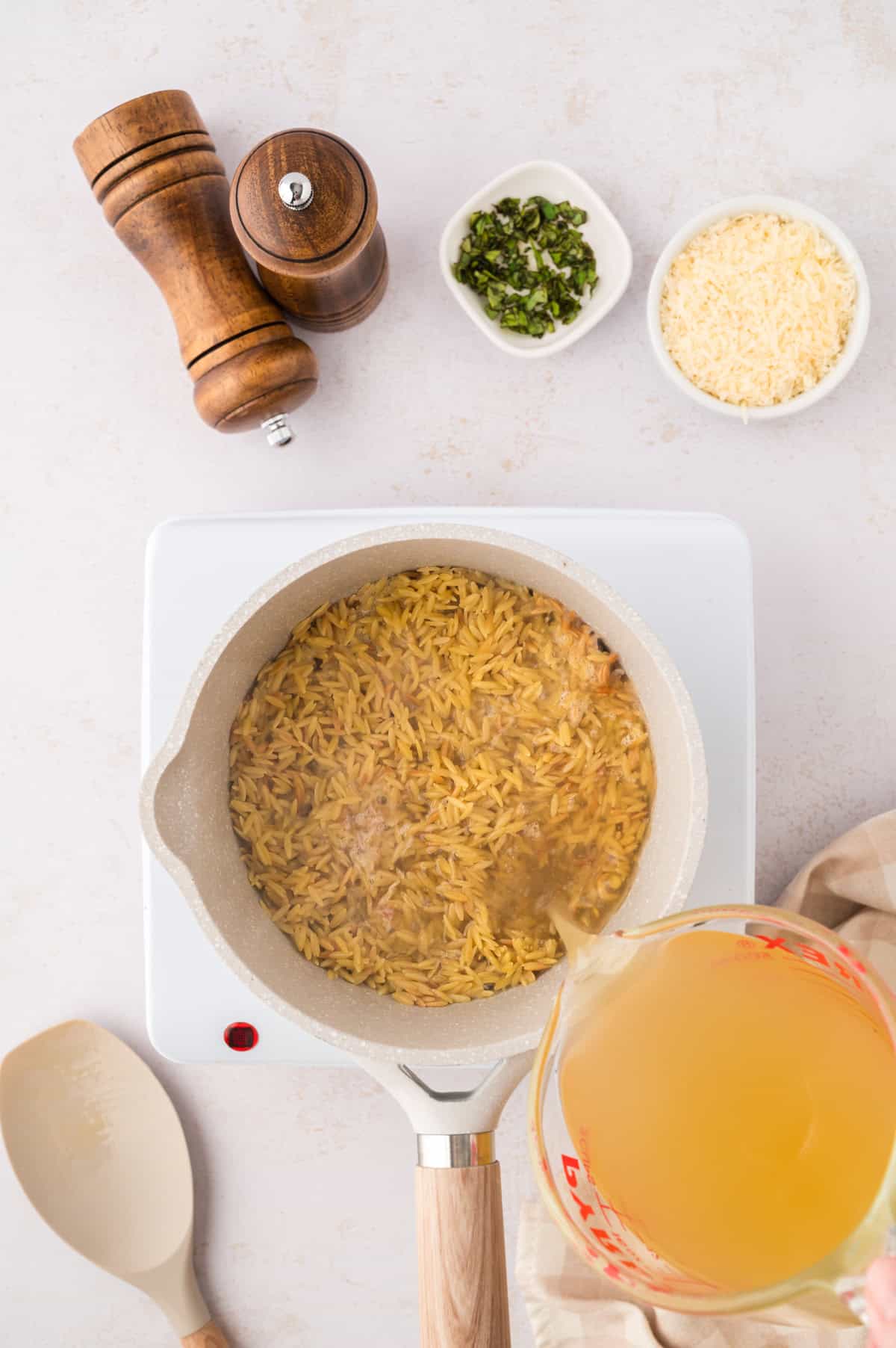 Chicken broth in saucepan with orzo.