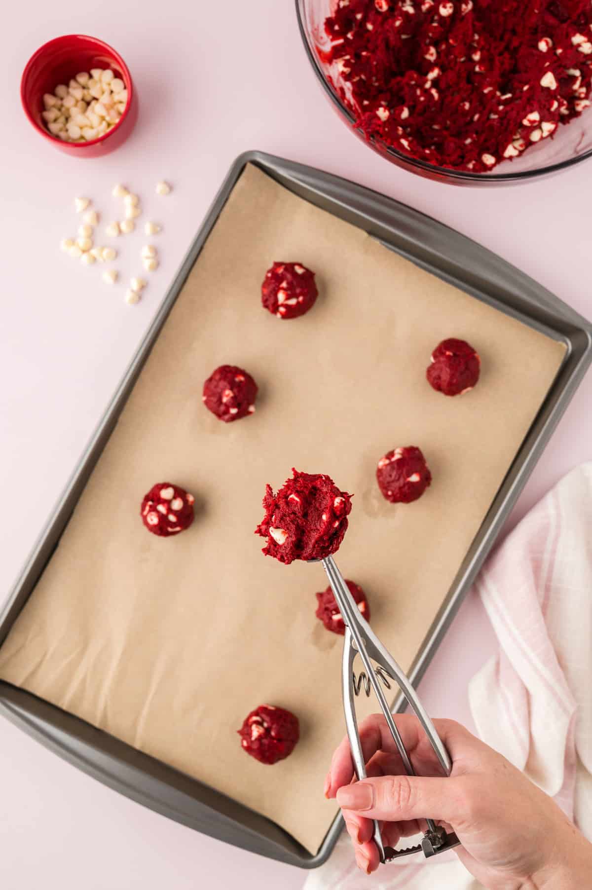 Cookie scoop dropping balls of cookie dough on baking sheet.