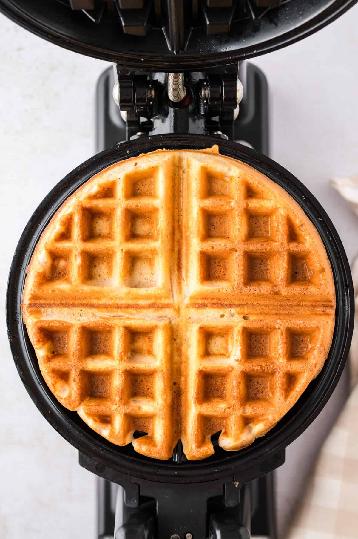 Belgian waffle cooking in waffle iron.