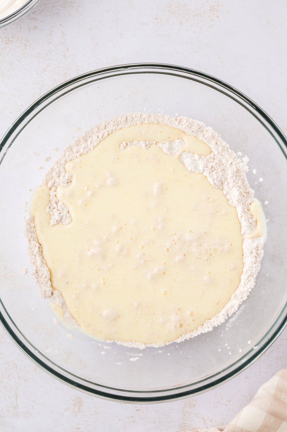 Wet and dry ingredients for waffles in mixing bowl.