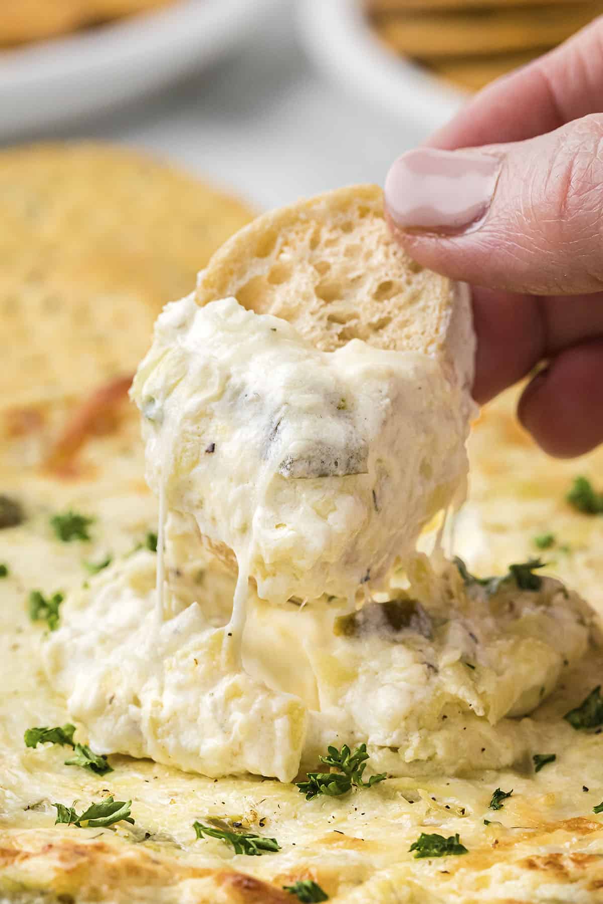 Artichoke jalapeno dip on piece of bread.