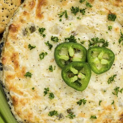 Artichoke jalapeno dip surrounded by crackers and vegetables.