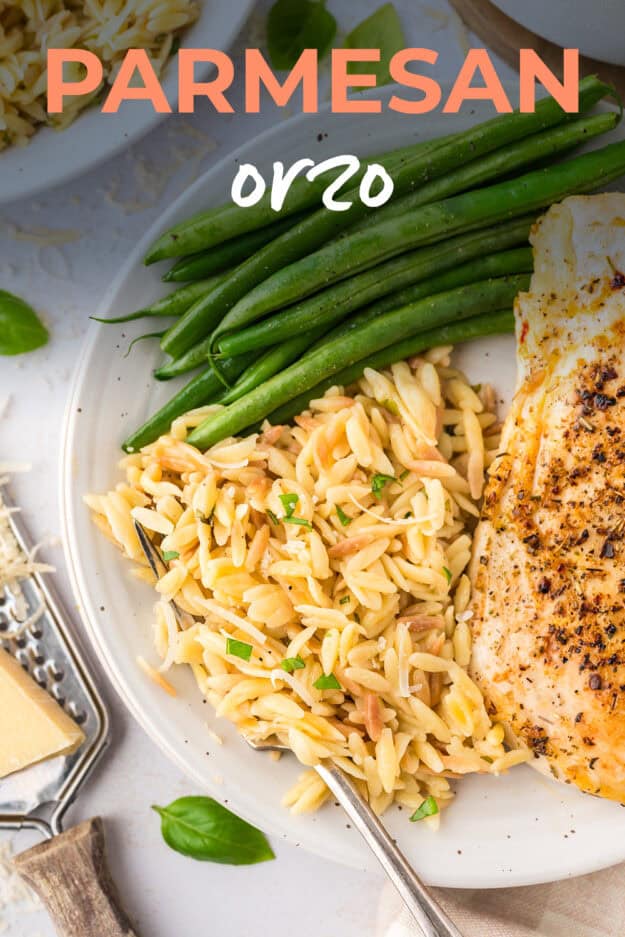 Parmesan orzo on plate with green beans and chicken.